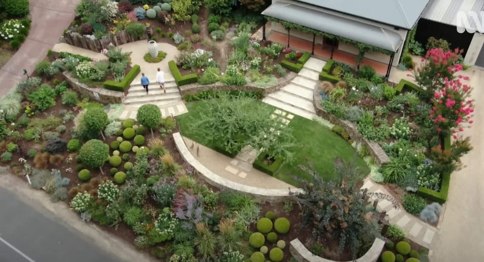 Multi-level landscape design with professional lawn care and structured garden beds Stunning aerial view of terraced garden with formal lawn, curved pathways, and lush plantings